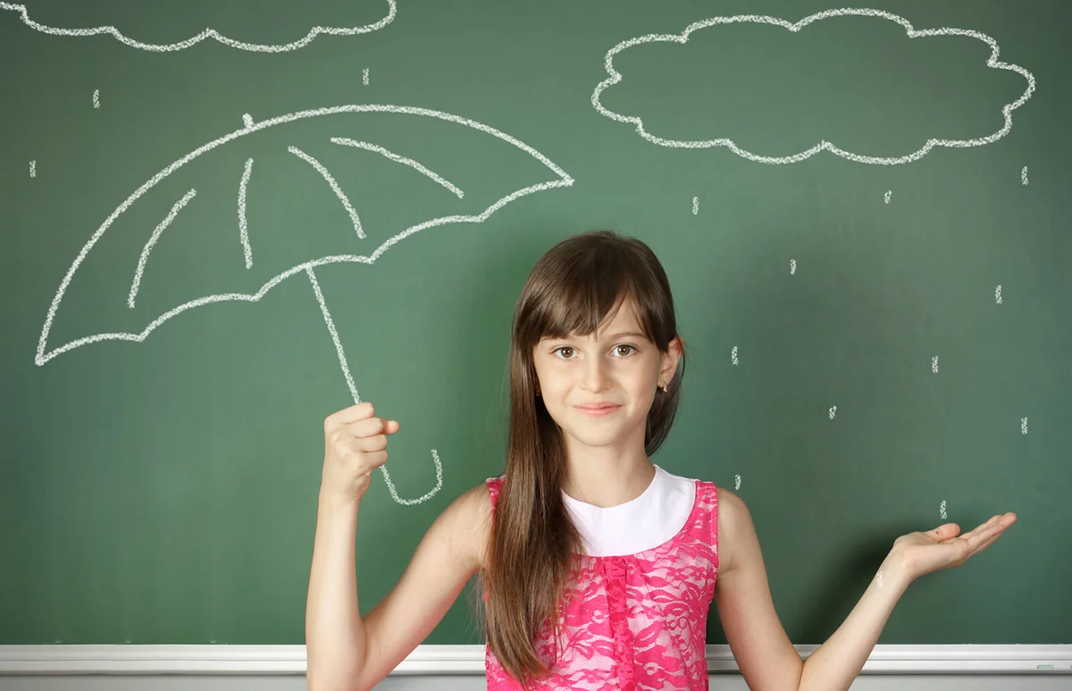 child hold umbrella near school blackboard
