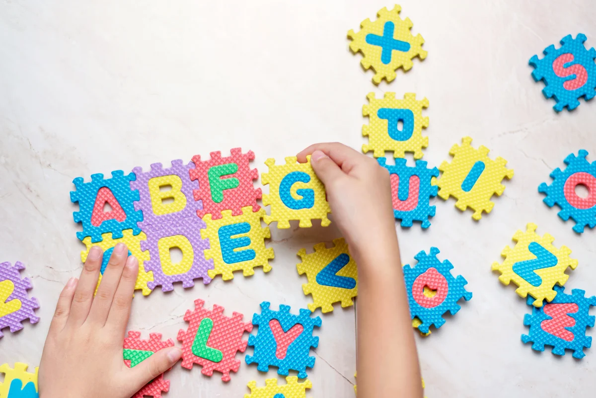 Child Playing With Alphabets On Puzzles At Floor
