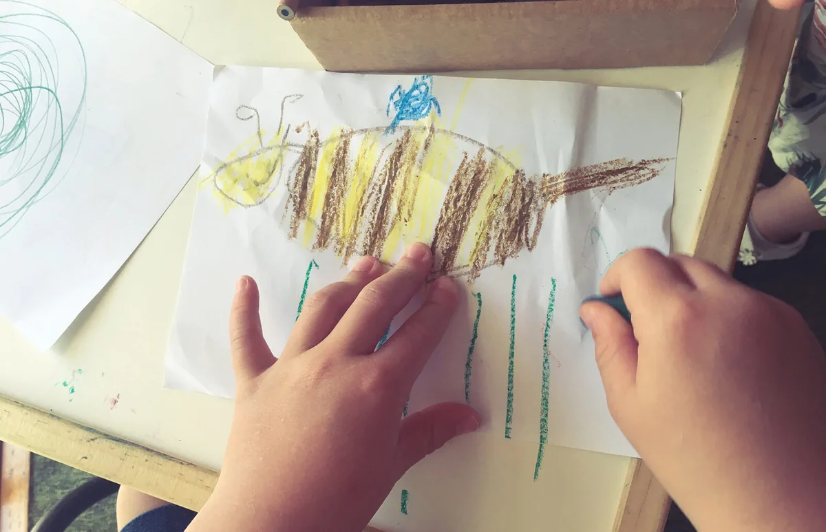 Child drawing a picture of a bee
