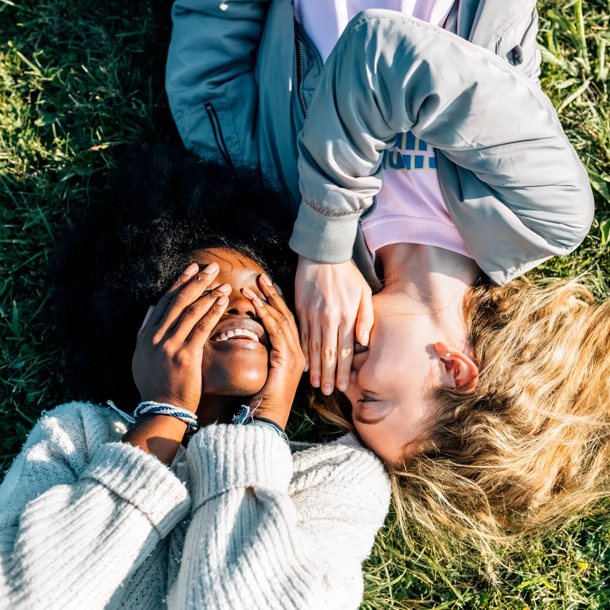 Two best friends telling secrets lying in the grass