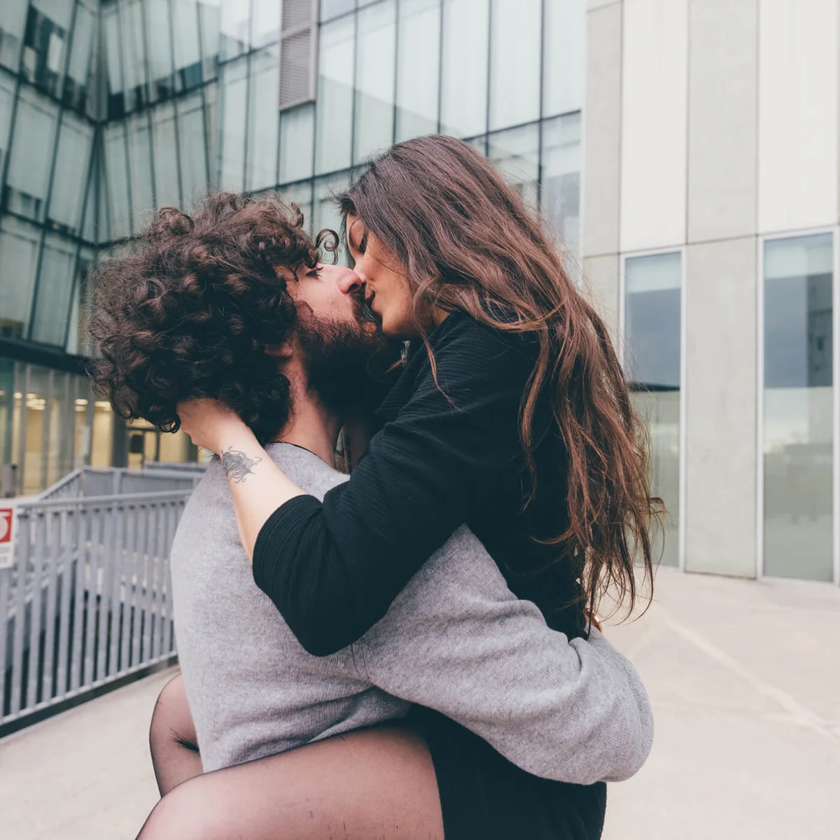 Young couple outdoors, kissing, woman's legs wrapped around man
