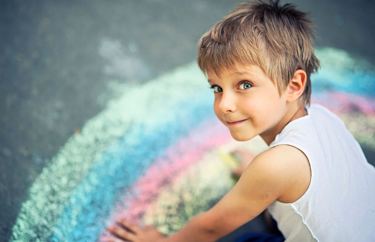 Little boy chalking rainbow