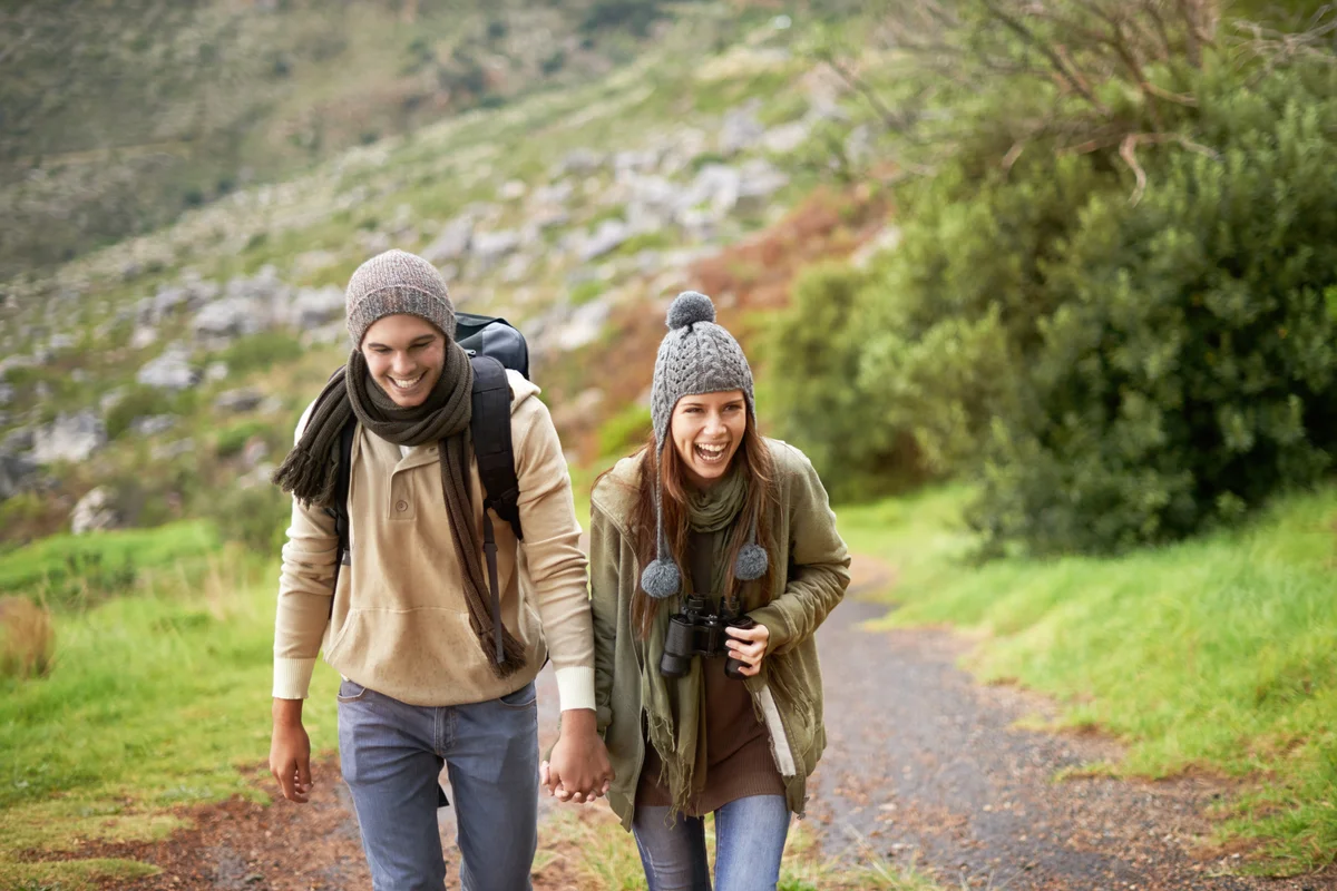 Young couple wrapped up warmly and hiking on a mountain trail together