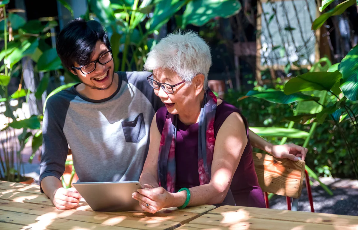 Young man teaching senior lady using tablet