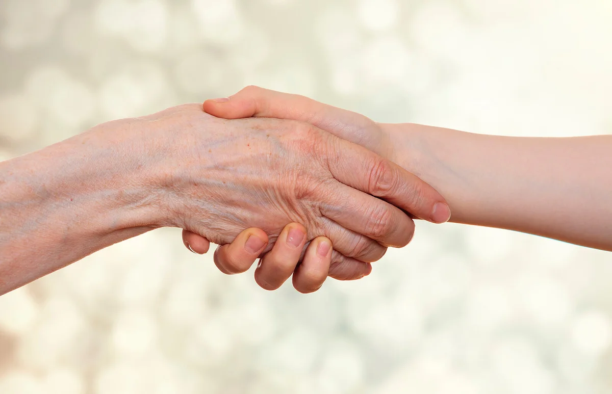 Handshake between an old person with a wrinkled hand and a kid