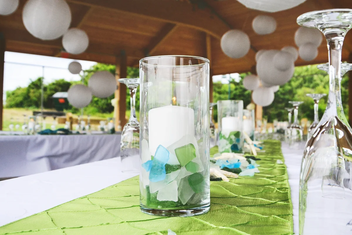 Centerpieces, candles, and champagne flutes on a sea green table runner