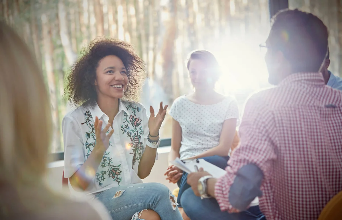 Smiling woman talking and gesturing in group therapy session