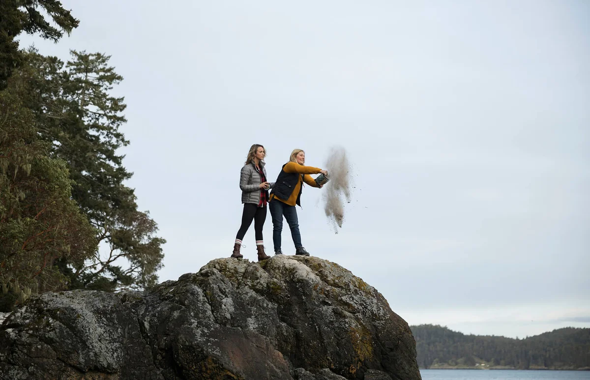 Mother and daughter spreading ashes on rocks