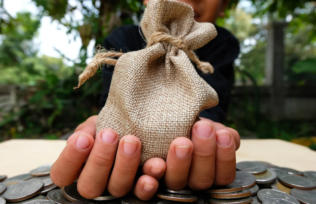 Close-Up Of Hand Holding Sack On Coins