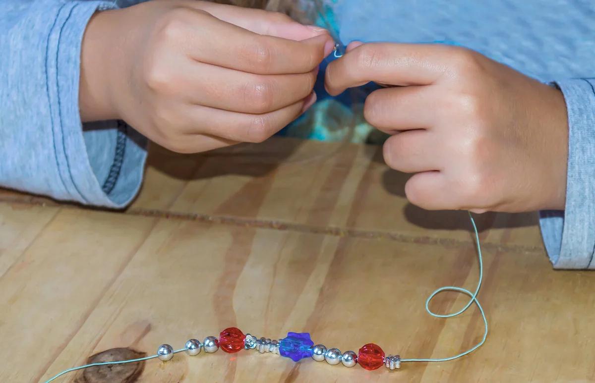 girl making a beaded bracelet