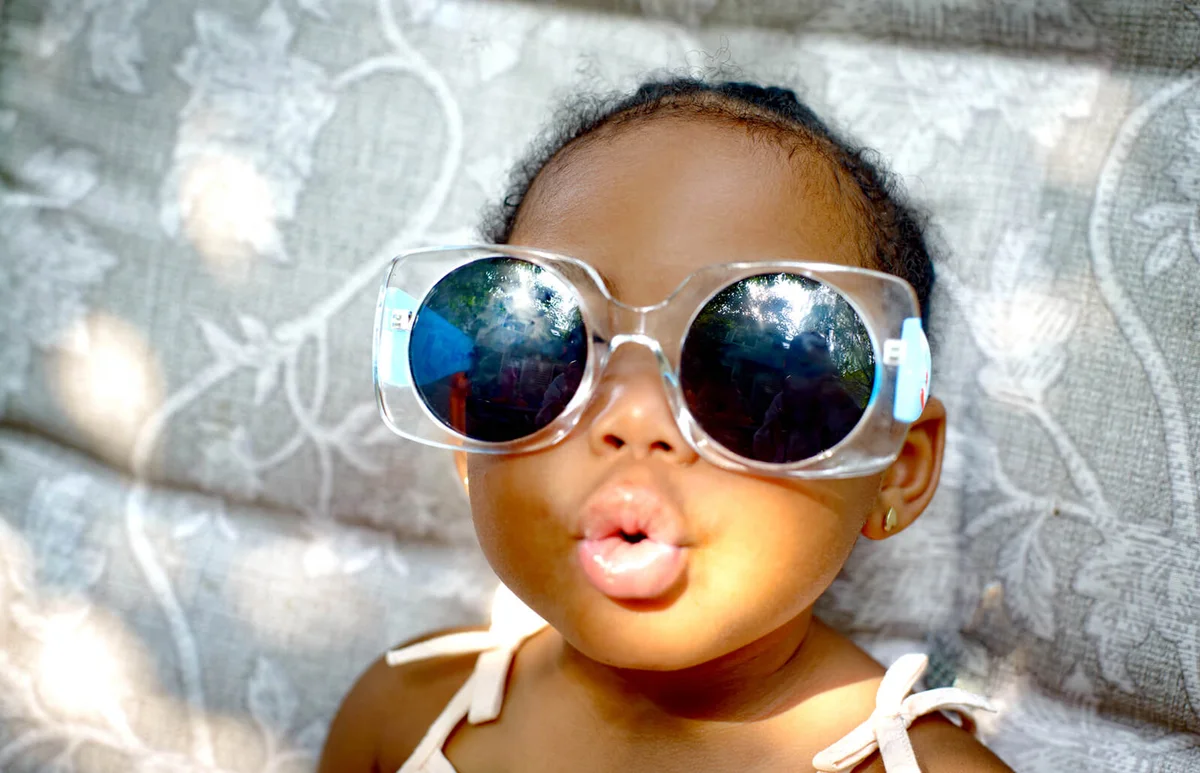 Baby girl sitting on lounge chair wearing sunglasses