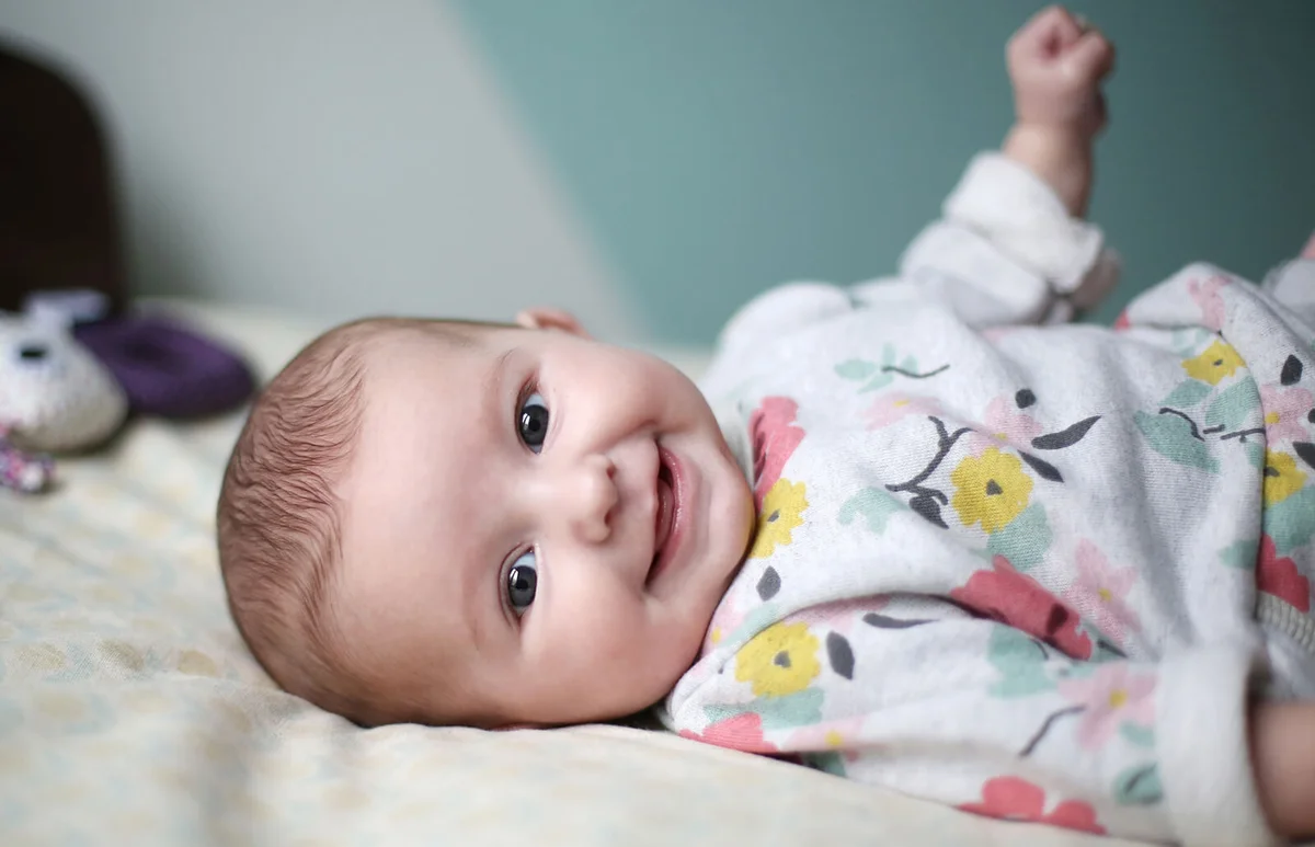 A baby girl smiling on a bed