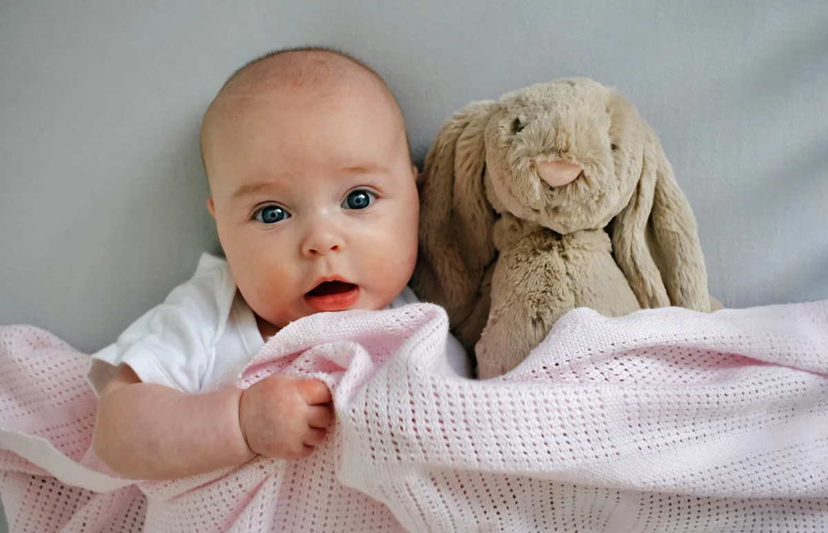 Baby in bed with soft toy