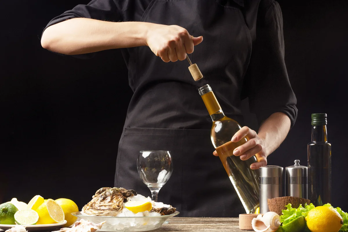 Chef opens Italian dry wine with oysters with lemon