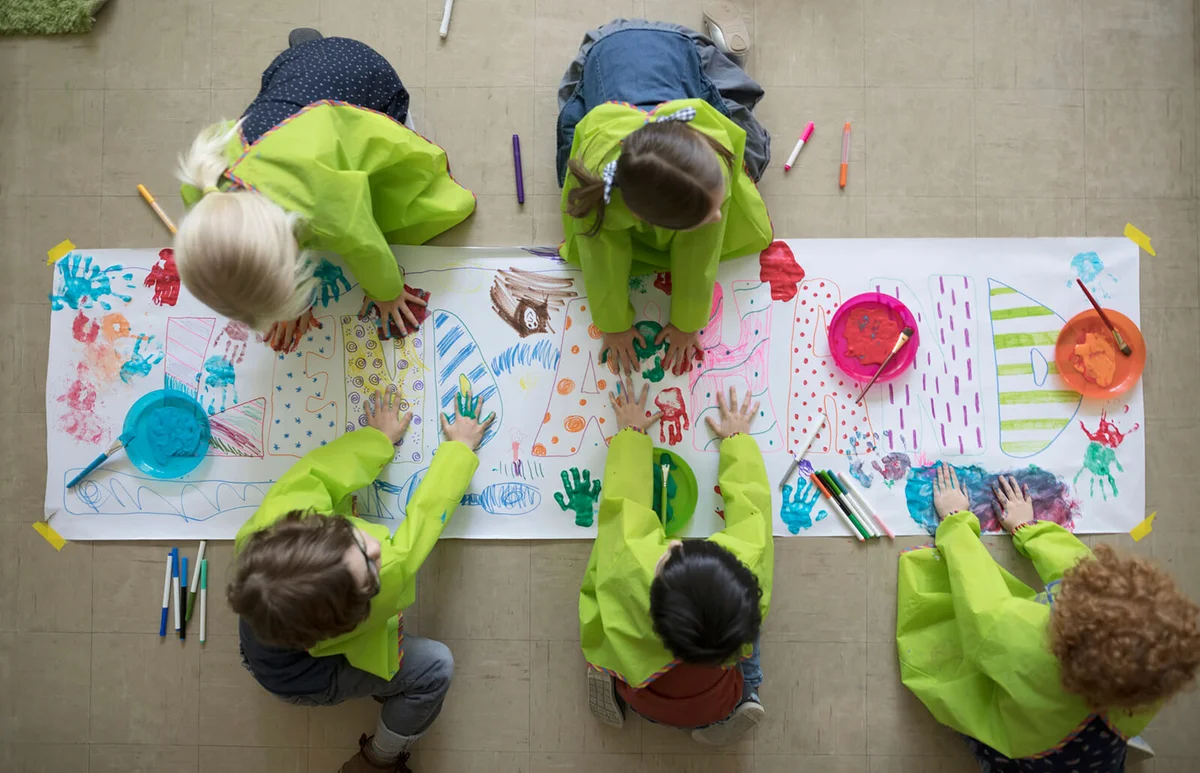 preschool students using finger paints on poster