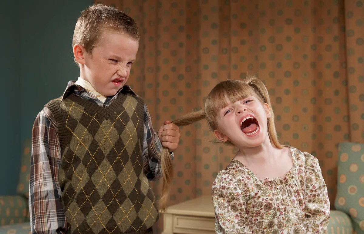 Boy pulling girl's hair in room