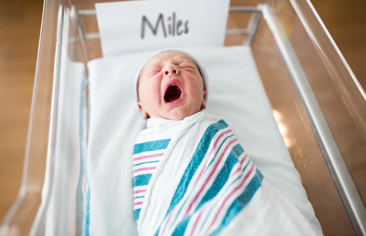 Newborn Infant Yawning in Crib