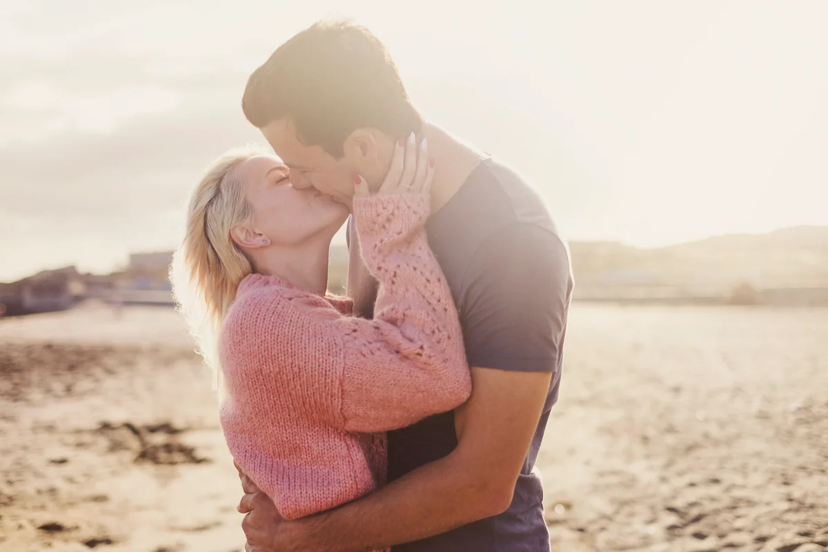 Romantic kiss for young couple hugging with sun backlight