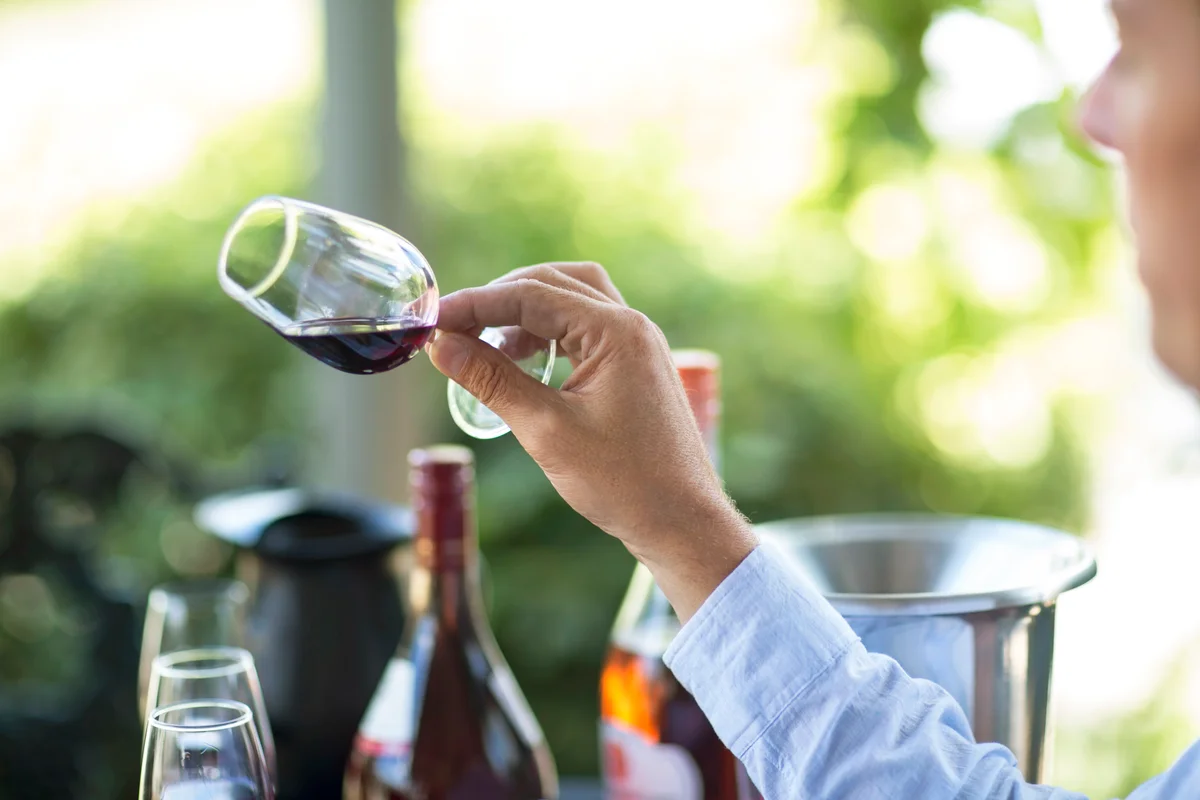 Man holding and judging glass of red wine