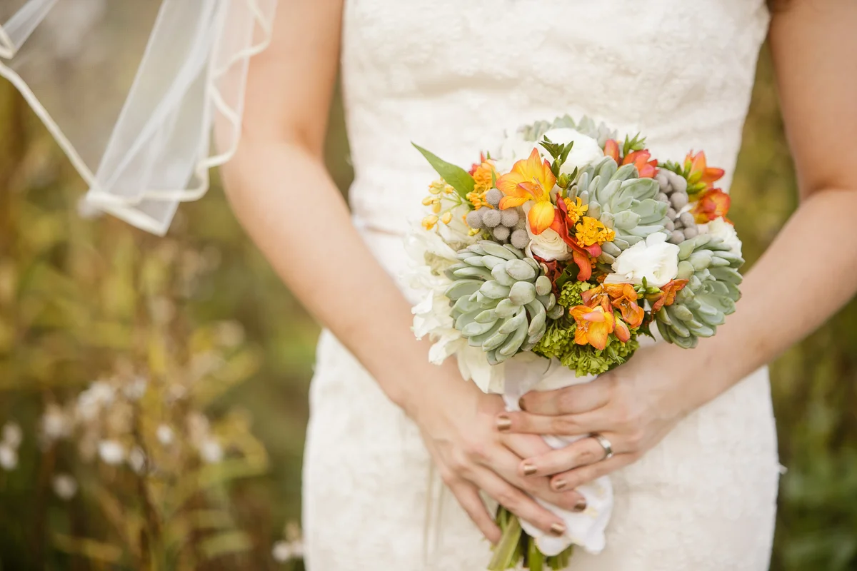 Bride holding wedding bouquet with Echeveria, Dahlia, and mini Hydrangea