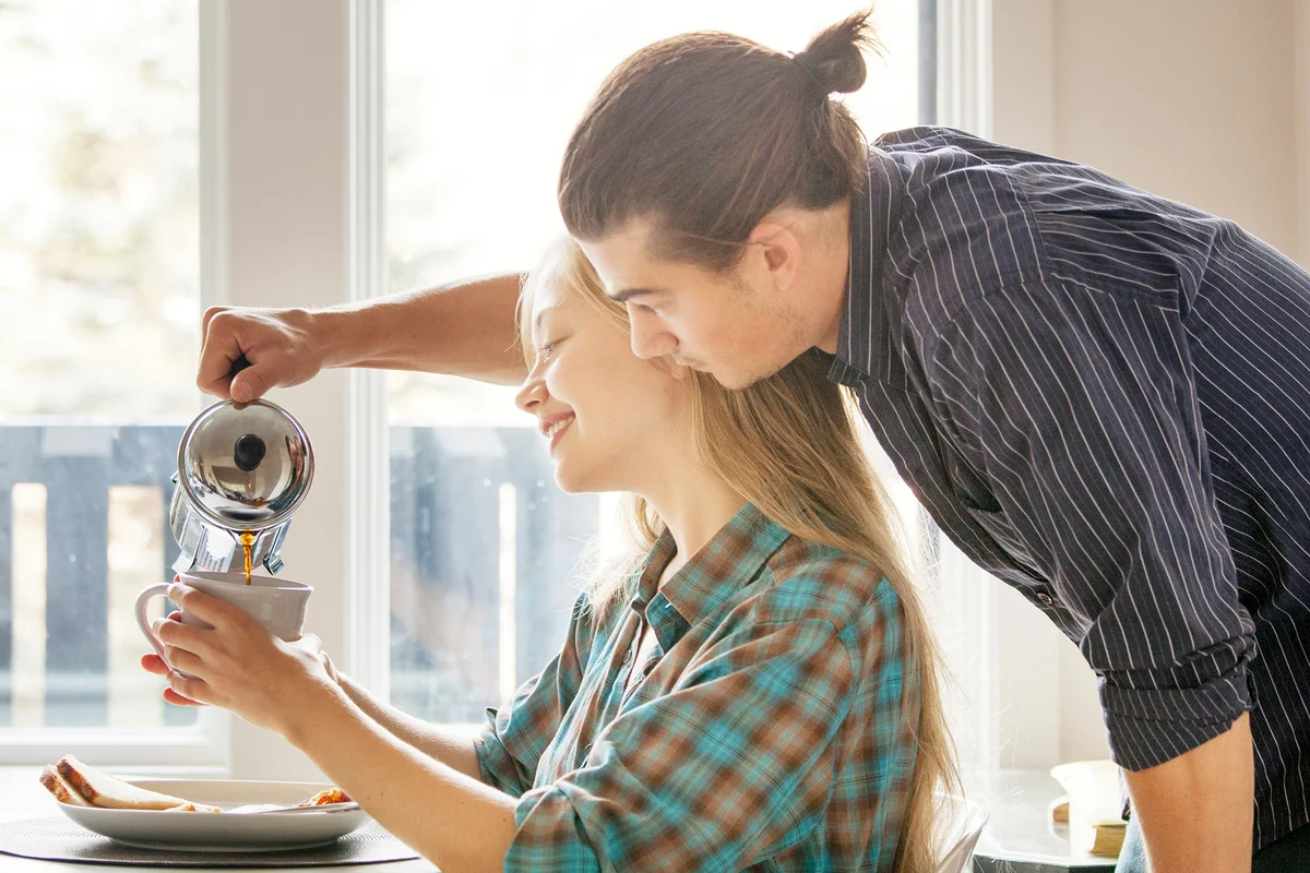 Man pouring coffee in cup for girlfriend at home