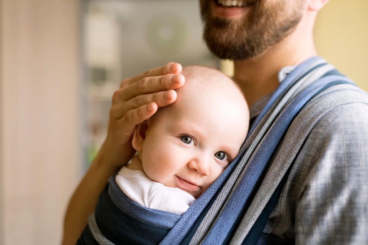 Father with baby son in sling at home