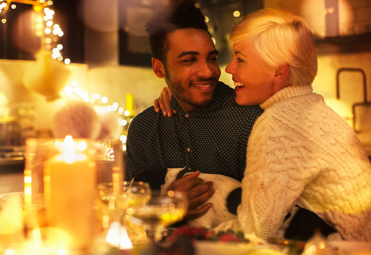 Affectionate couple with dog at candlelight Christmas table