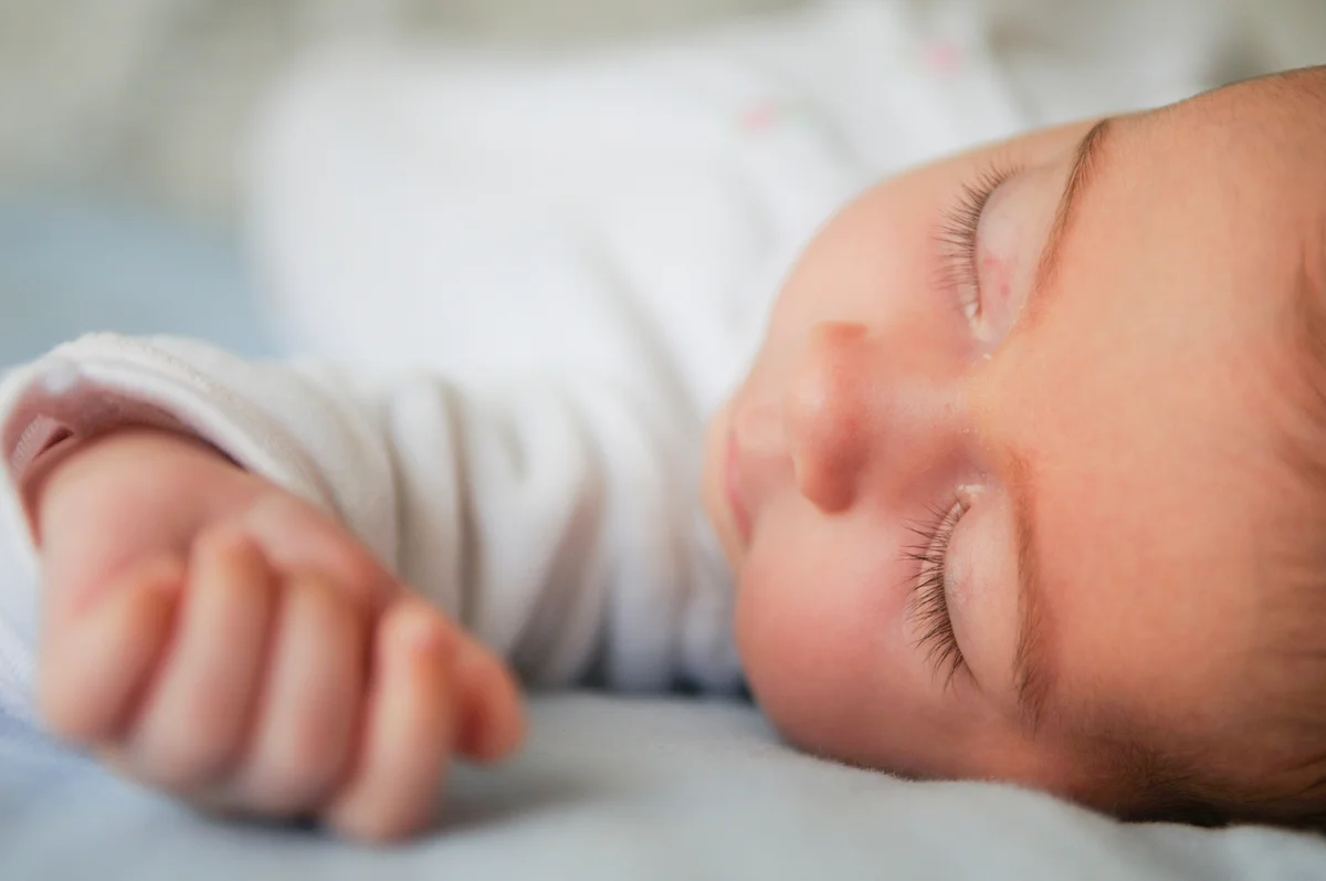 Close-Up Of Cute Baby Girl Sleeping On Bed