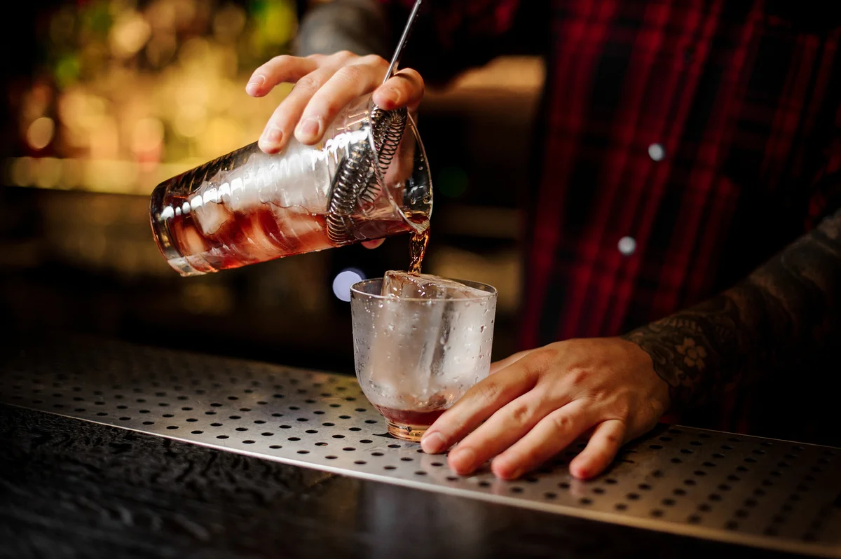 Straining a vieux carre cocktail into a rocks glass.
