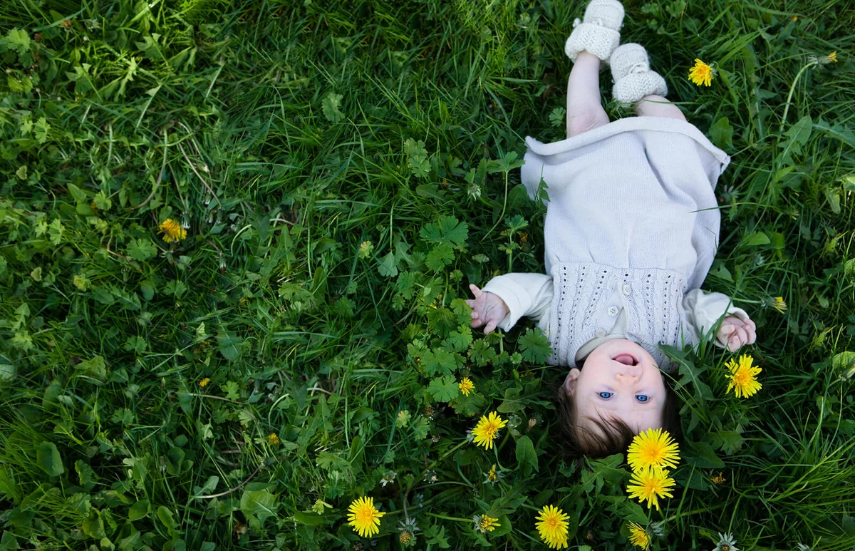 A cheerful baby girl lying in the grass