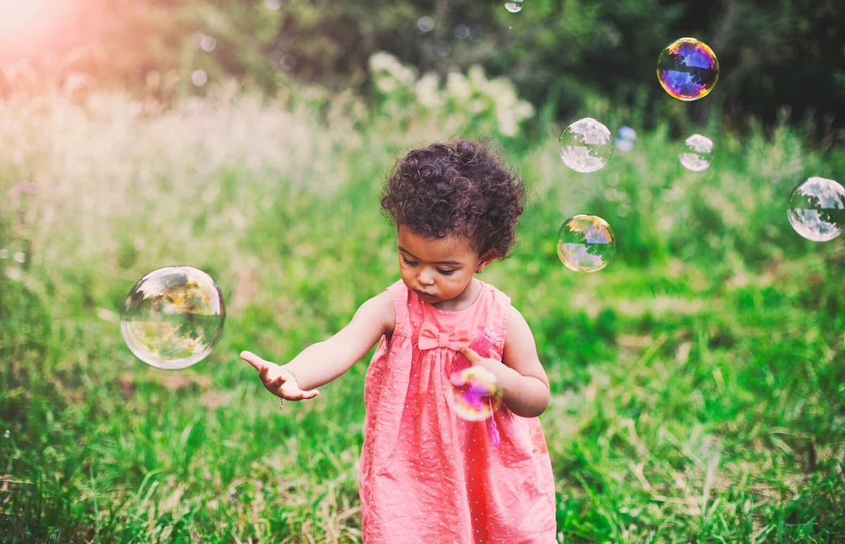 baby girl playing with soap bubbles in the park