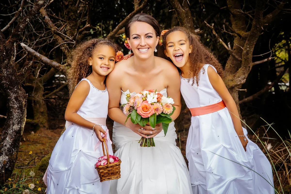 Flower girls smiling with bride outdoors