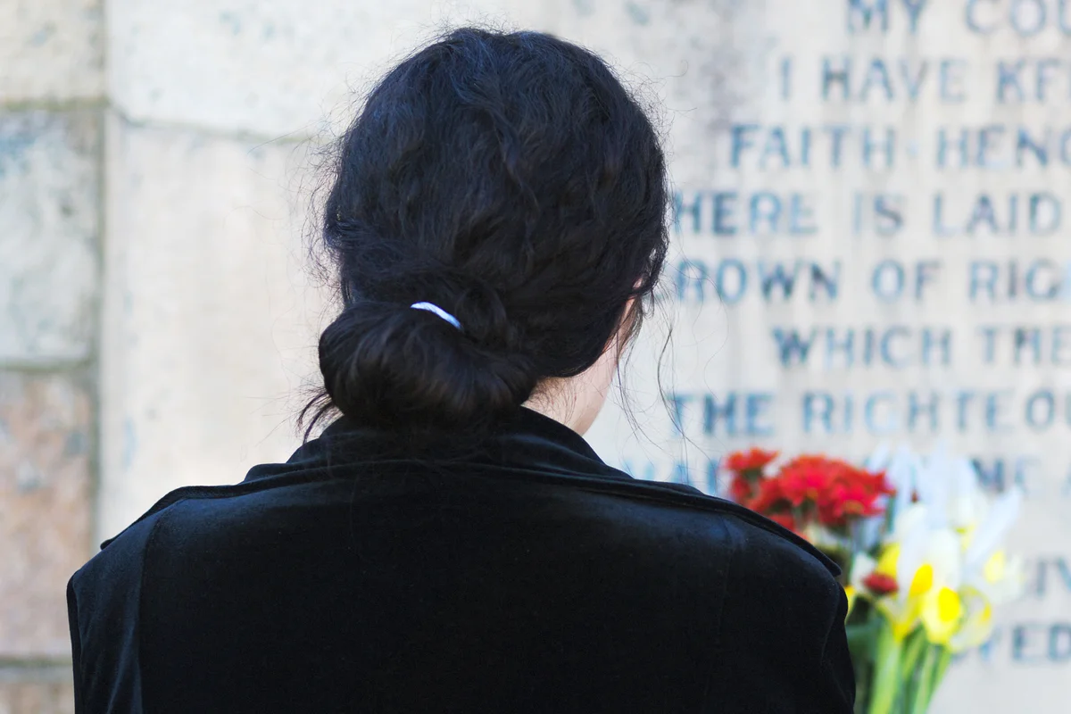Rear view of woman by gravestone with flowers