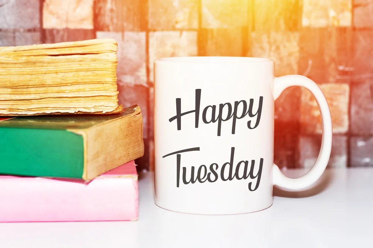 Happy tuesday word on white morning coffee cup and books