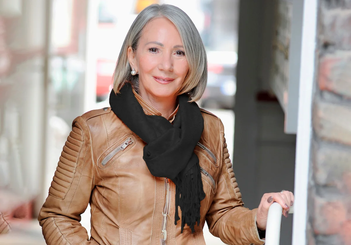 Senior woman in leather jacket and scarf opening door
