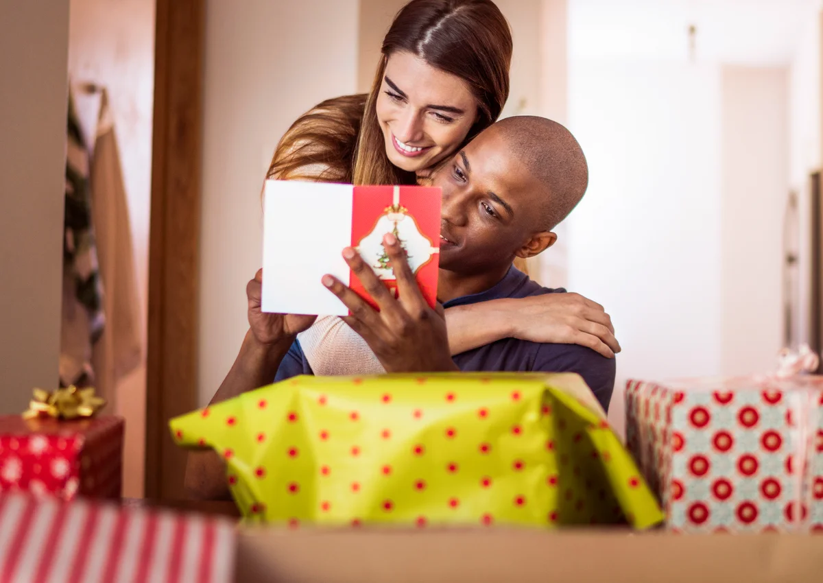 Woman embracing boyfriend while reading card