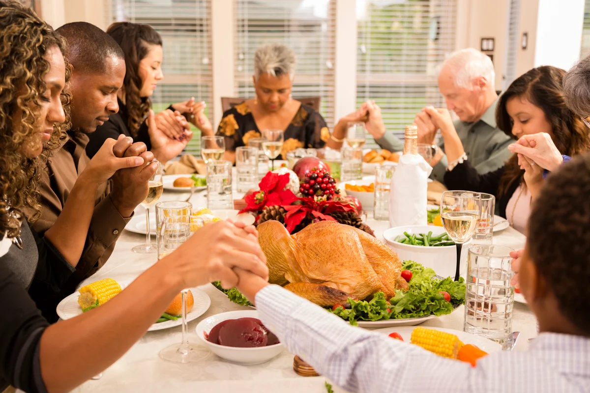 Family praying before eating Thanksgiving dinner