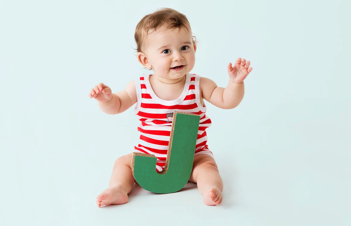Baby boy playing with cardboard letter J