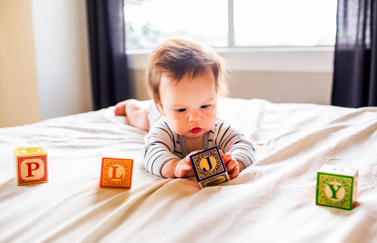 baby girl playing with blocks on bed