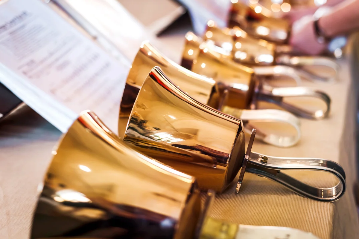 Golden handbells on table with sheet of notes