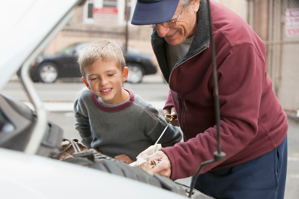man with grandson checking oil in car