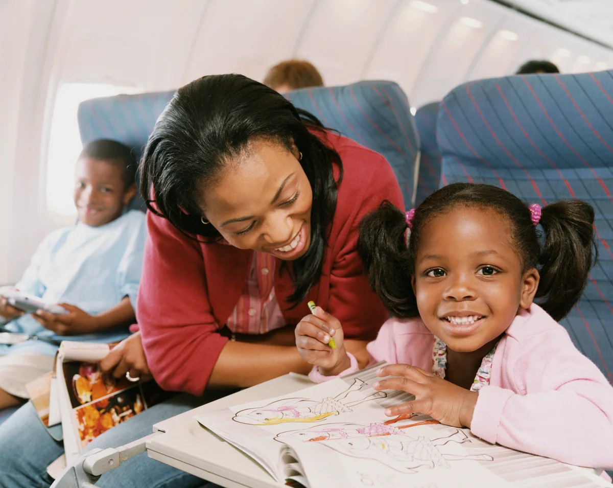 Mom and daughter on plane trip coloring in book