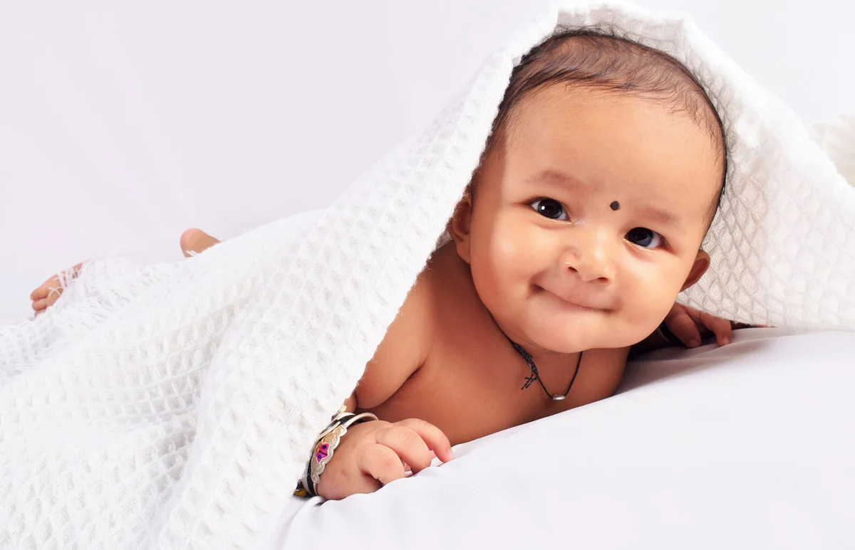 Cute baby sleeping on bed on stomach laughing