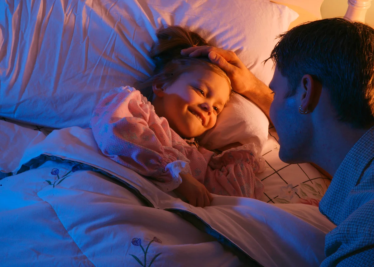 Father tucking daughter into bed