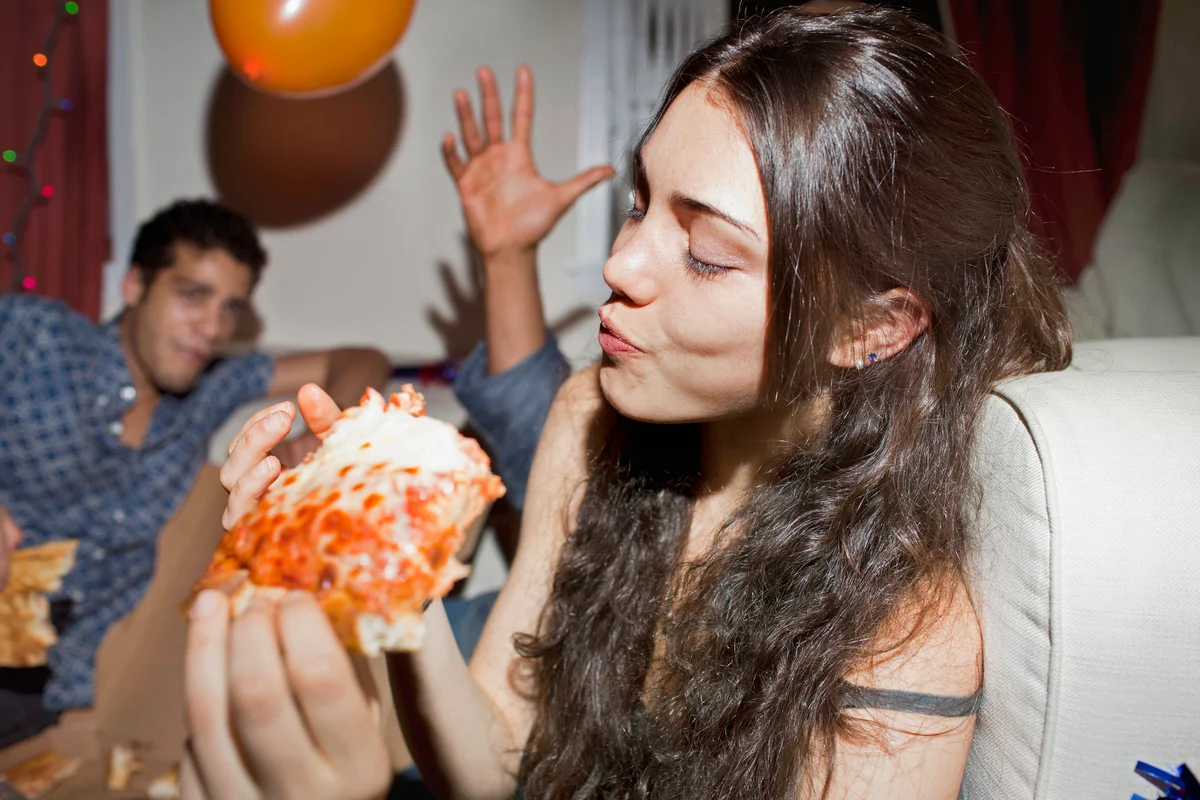 Young woman eating pizza at a party
