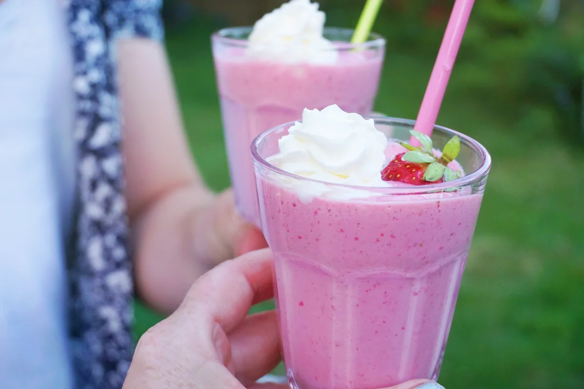 People drinking strawberry milkshakes