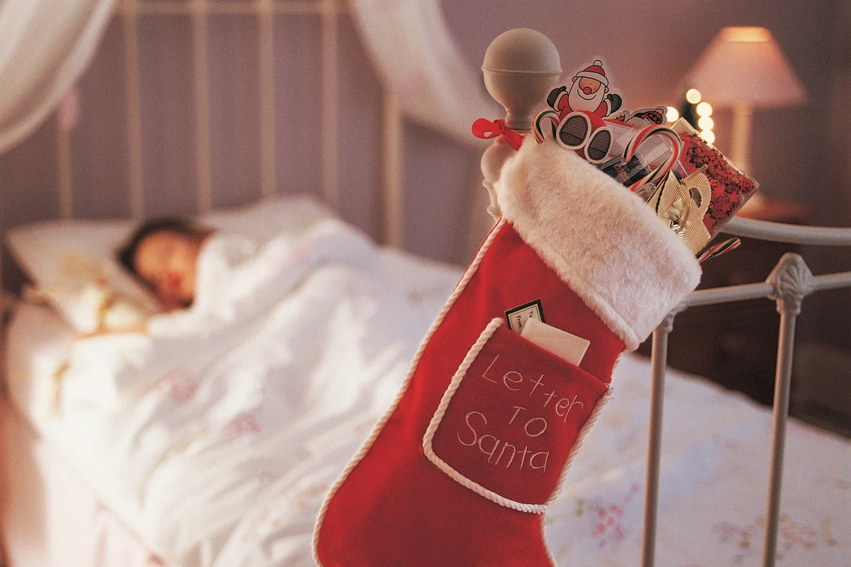 Christmas Stocking Hanging on a Bed Knob and a Child Sleeping in Bed in the Background