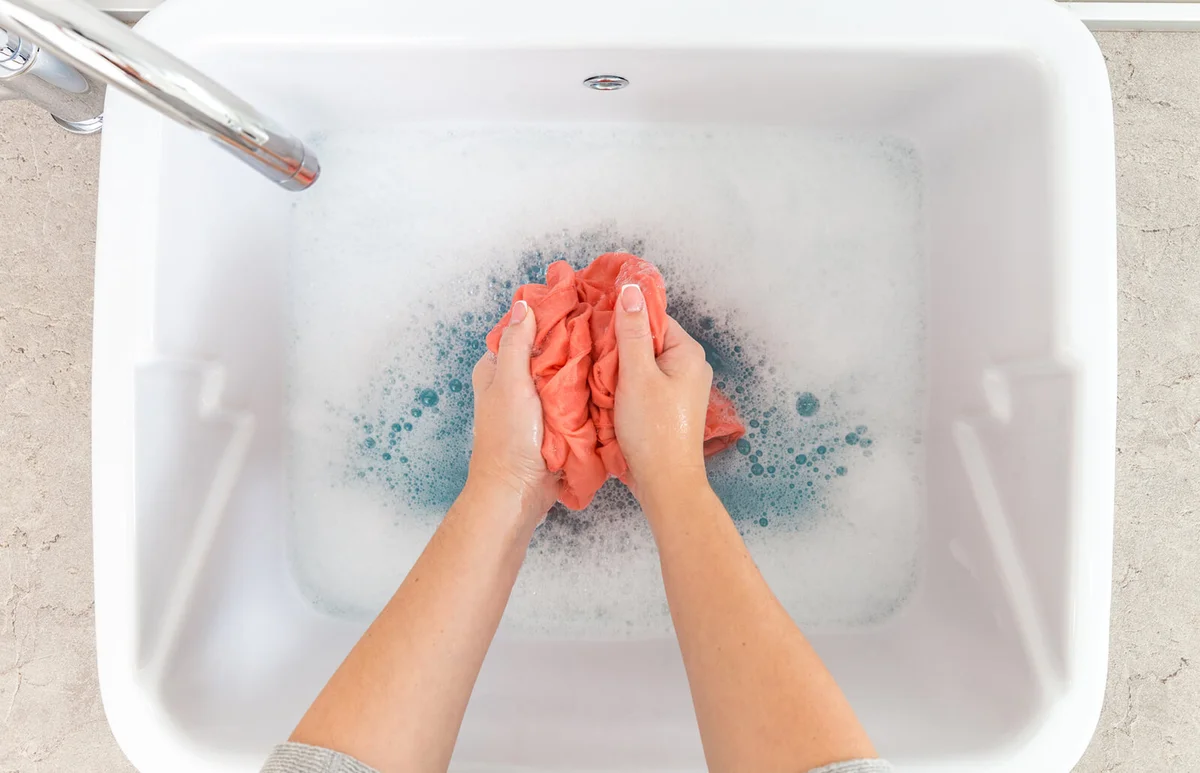Female hands washing color clothes in sink