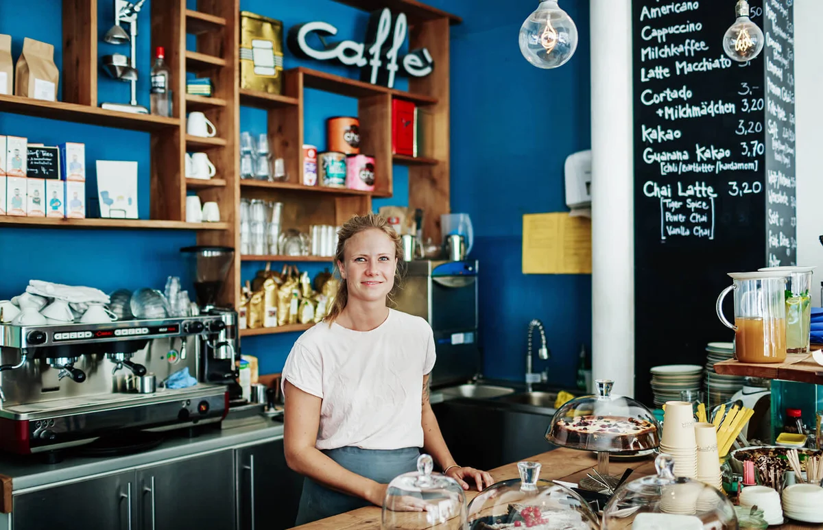 Waitress Standing At Her Coffee Shop Counter