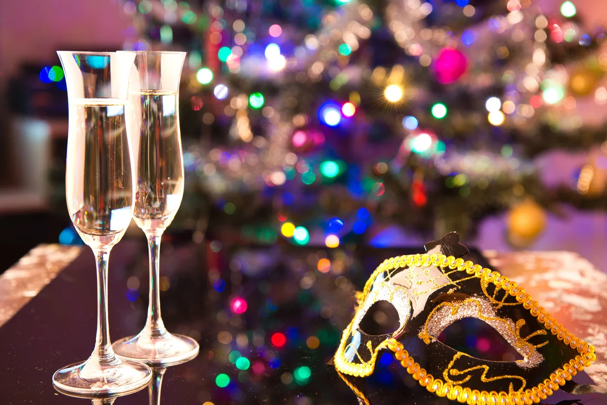 Two glasses of champagne and a black carnival mask